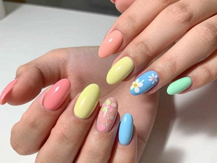 Colorful almond nails featuring pink, yellow, mint green, baby blue, and white daisy accent nail.